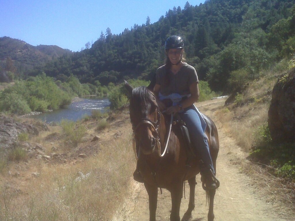 Heidi riding her horse Harley on a mountain trail