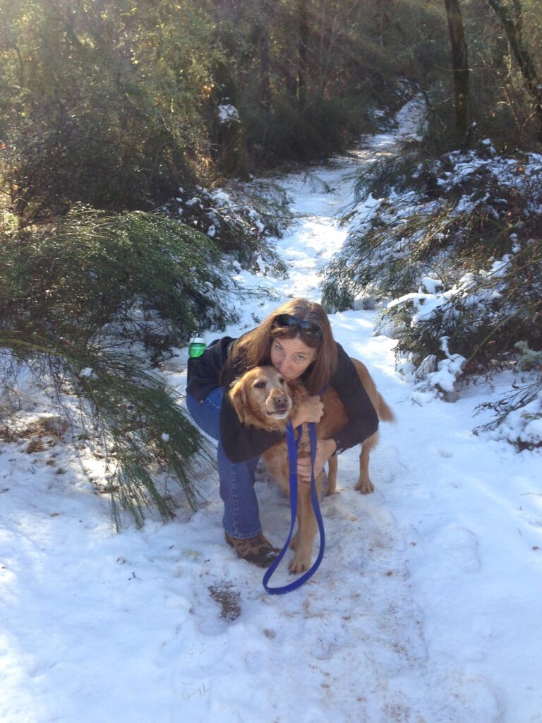 Heidi hugging her dog on a snowy trail